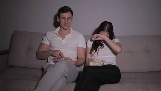 夫妻坐在沙发上一起看恐怖电影视频素材模板下载