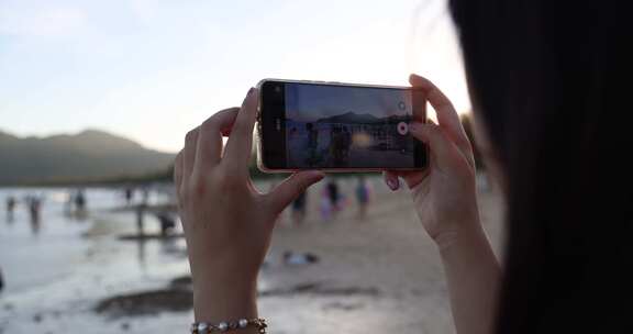 美女在海边用手机录视频