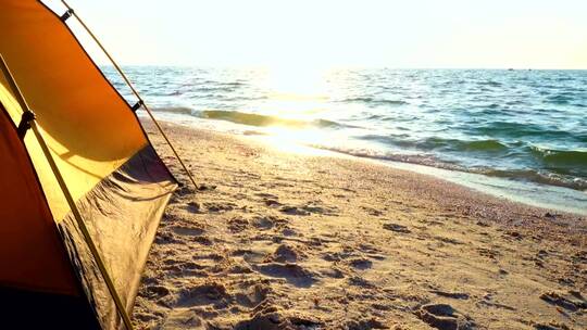 日出时在海滩上露营的帐篷