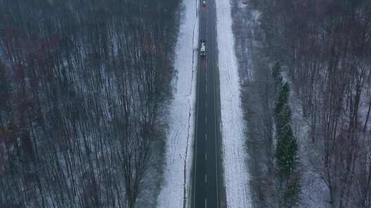 冬季森林里雪地公路上行驶的汽车