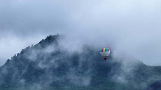 飞在云雾缭绕群山之中的热气球