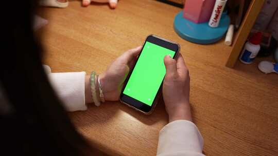 女孩在宿舍书桌前玩手机 手机绿布合成视频素材模板下载