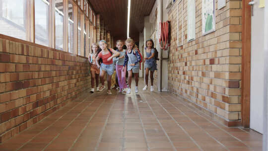 小学走廊里背着书包的快乐多样化女学生