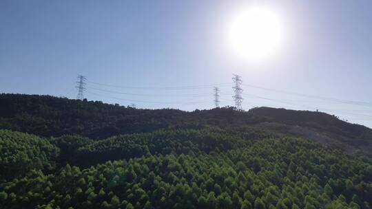 阳光下电塔航拍山上电网森林山区电线电力塔视频素材模板下载