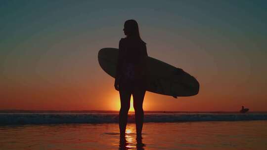 海边夕阳下拿着冲浪板的女孩视频素材模板下载