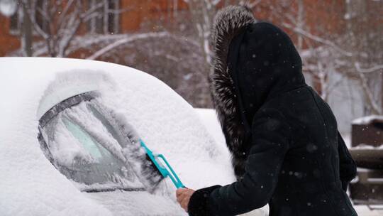 女人在冬天打扫车上的雪