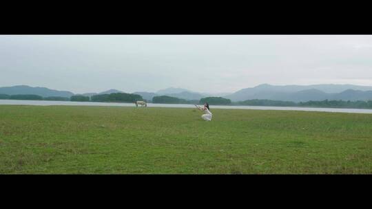 白色连衣裙女子在草原上旋转跳舞