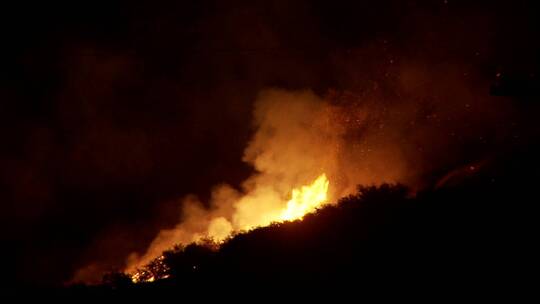 消防队员在晚上通过从空中油轮上表演水滴来对抗肆虐的加州野火