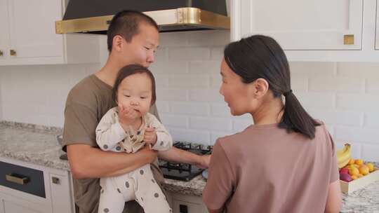 可爱的亚洲夫妇与他们蹒跚学步的孩子在厨房