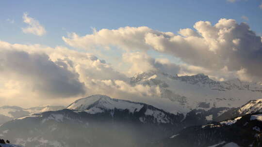 延时摄影显示了白雪覆盖的山脉上的云运动，在法国阿尔卑斯山的夜光下。