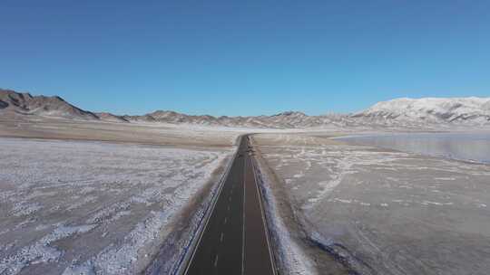 航拍冬季新疆赛里木湖环湖车辆行驶雪山公路视频素材模板下载