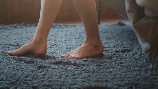 女人赤脚走下床，踩在柔软的地毯上
