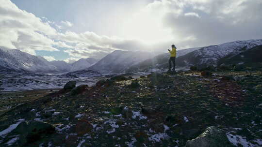 强壮的徒步旅行者在山顶用智能手机拍照。奇妙的黎明