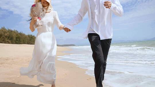 情侣牵手奔跑在海边沙滩