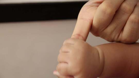 婴儿握着大人的手指