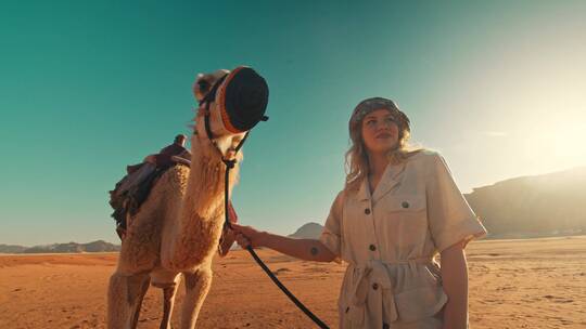 女人手牵骆驼在沙漠中拍照视频素材模板下载