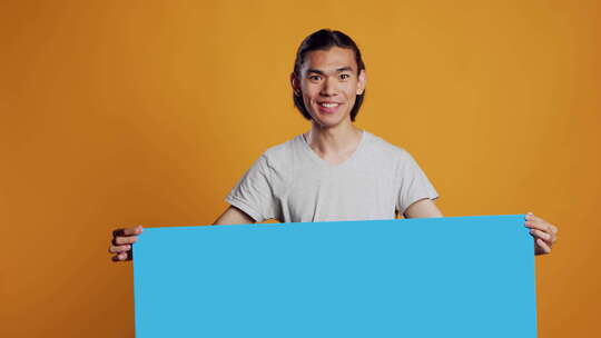 亚洲年轻人拿着相机上的蓝色纸箱板