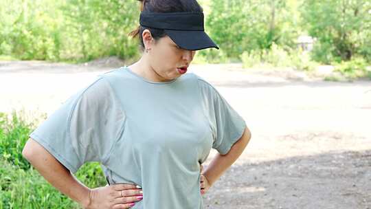 年轻女子在夏季公园慢跑后闻到并试图呼吸