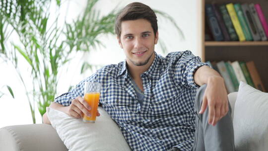 帅哥坐在沙发上喝果汁微笑