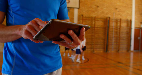 篮球教练在学校篮球场使用数字平板电脑