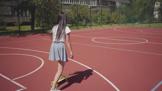 女孩在篮球场地上玩滑板视频素材模板下载