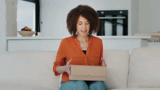 兴奋的非洲卷发女人顾客女买家在家打开包裹箱坐在