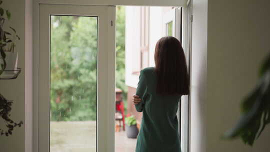 沮丧的女人透过窗户凝视着雨