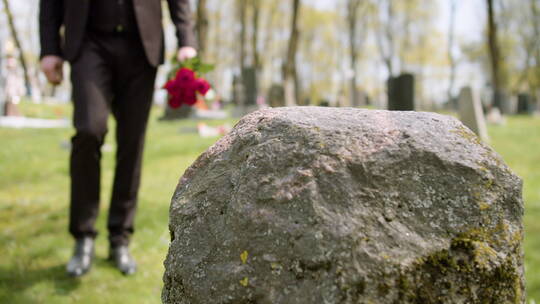 将鲜花放在墓碑上的男人