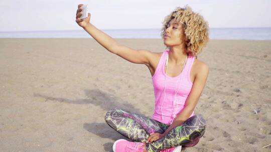 女人坐在海滩上使用手机自拍视频素材模板下载