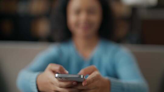 笑着的非裔美国卷发女人在智能手机上阅读消视频素材模板下载