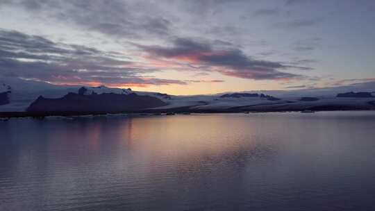 日落时海洋中的单一冰川被雪山空中包围