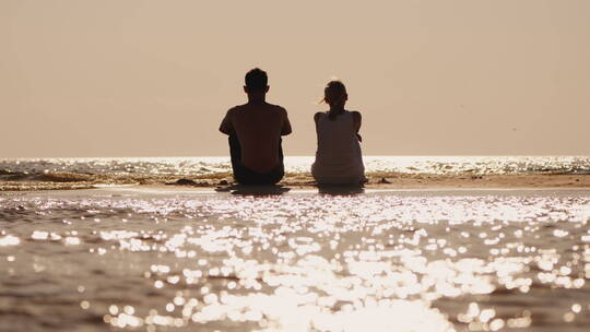 在沙滩上看着 日落的夫妻