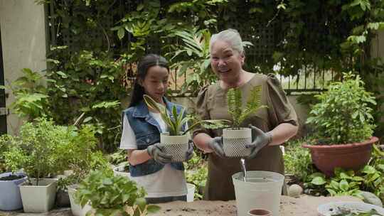 祖母和孙女在后院抱着盆栽植物的肖像