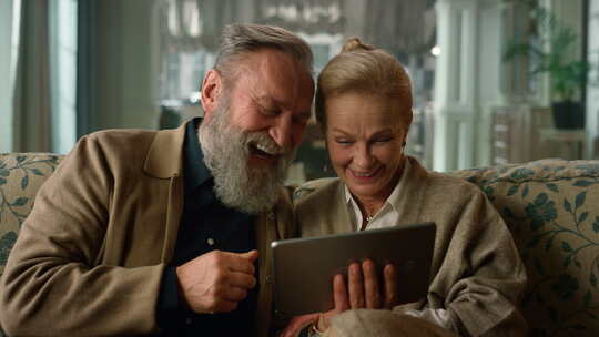 兴奋的老年夫妇在家看平板电脑幸福的家庭在