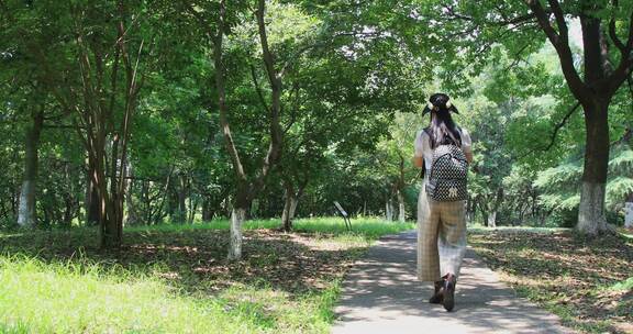 亚洲年轻时尚女性背着包包走在公园的背影