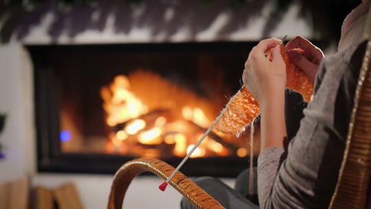 女人坐在壁炉旁织围巾