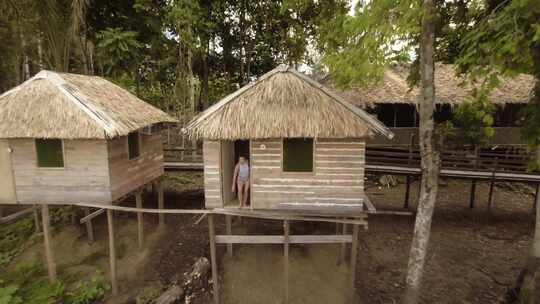 一个女人走出水边村庄的小屋，挥舞着天线