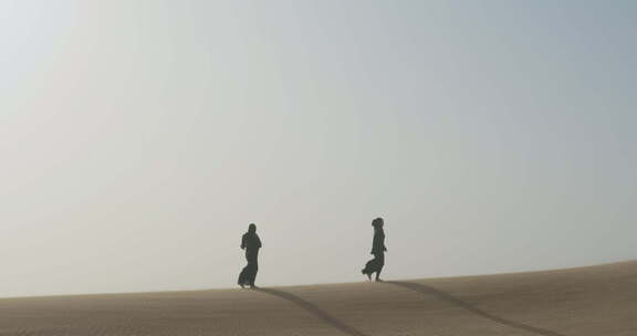 妇女在多风的沙漠中行走