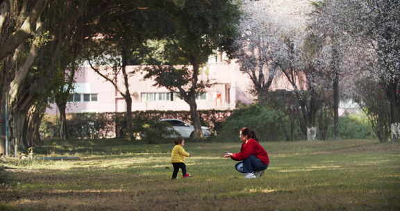 小朋友和妈妈在春天的公园里玩耍学步