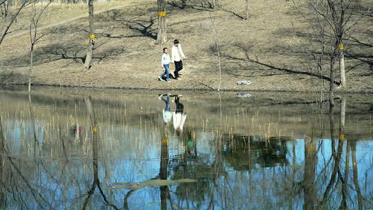 初春在公园河边散步的中国母女