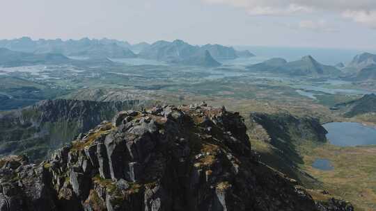 人们坐在海岸天线附近的岩石山顶上