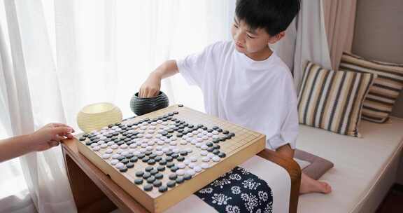 可爱的男孩在窗边下围棋