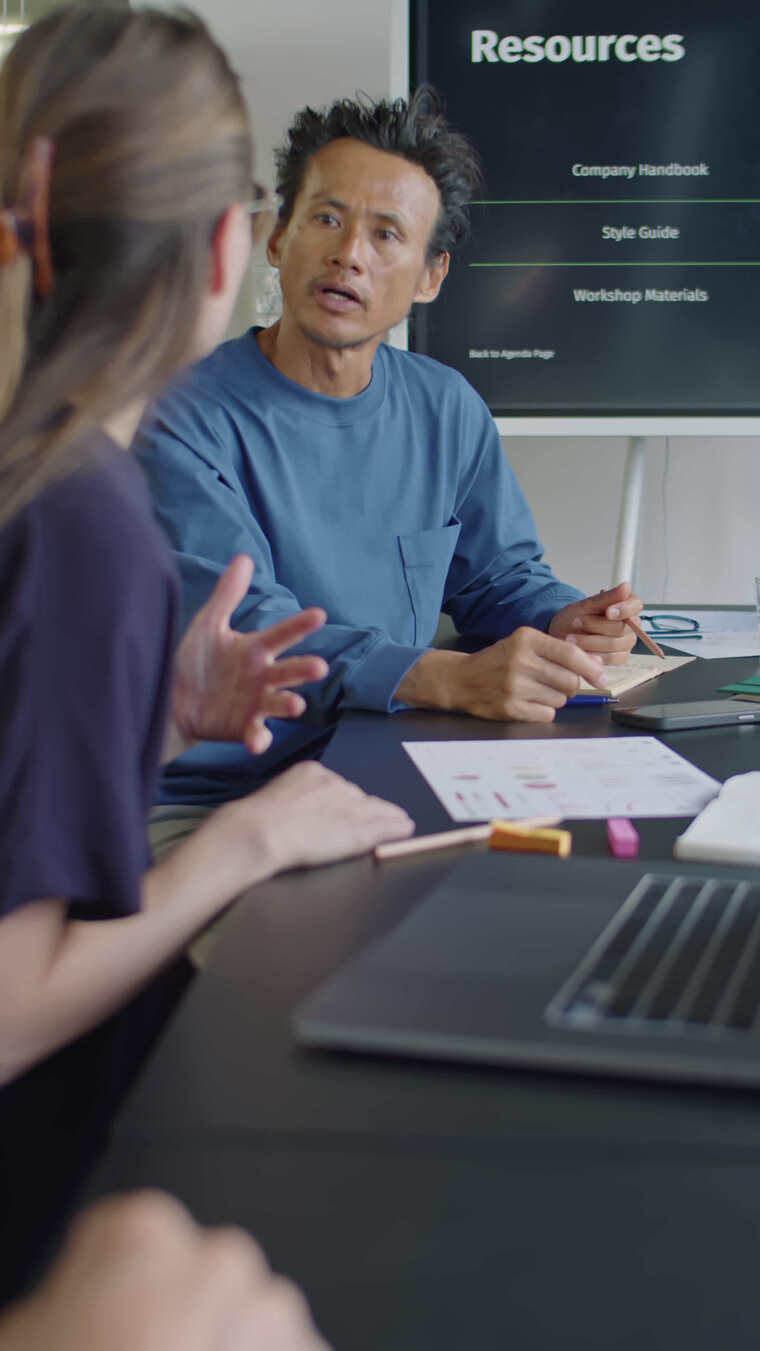 亚洲男子在会议桌上与同事交谈