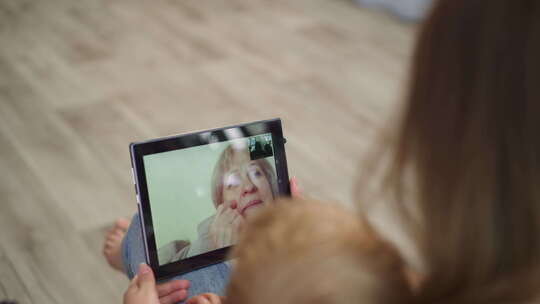妈妈和孩子通过现代平板电脑与奶奶视频通话