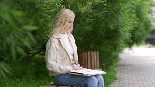 公园里用笔记本电脑工作的年轻女人