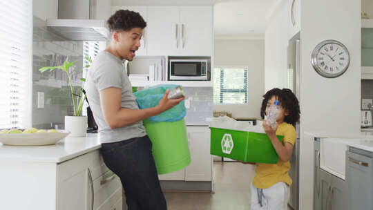 快乐的混血儿和他的儿子在厨房分类垃圾