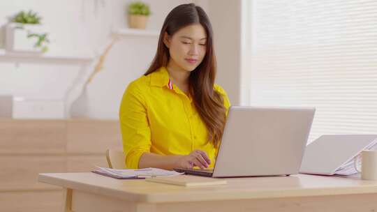女子穿着黄色衬衫用笔记本电脑工作