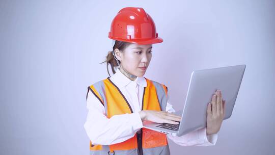 戴着安全帽的女工程师使用笔记本电脑