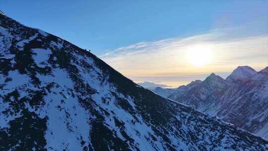 航拍日出时分攀登雪宝顶雪山的登山队