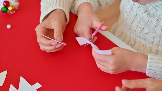用剪刀剪纸树和装饰品的孩子特写